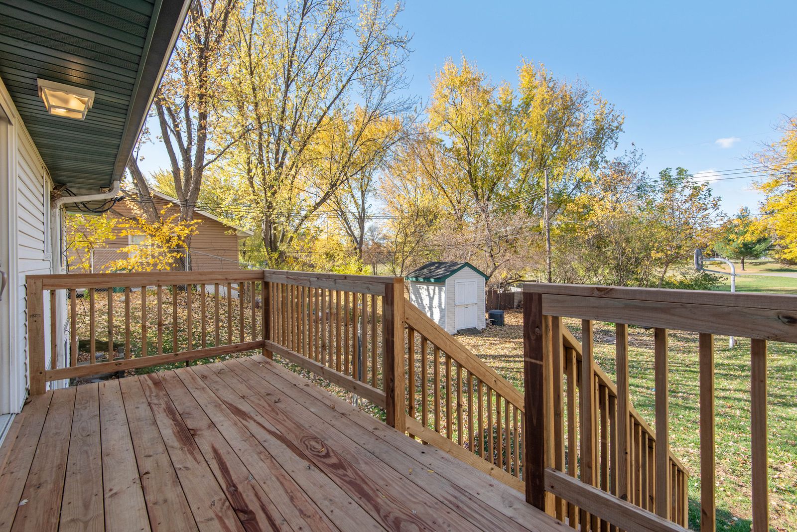 A wooden deck with board railings and steps leading down to a backyard lawn